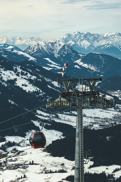 During the day, red and black cable car on the snowy mountain
